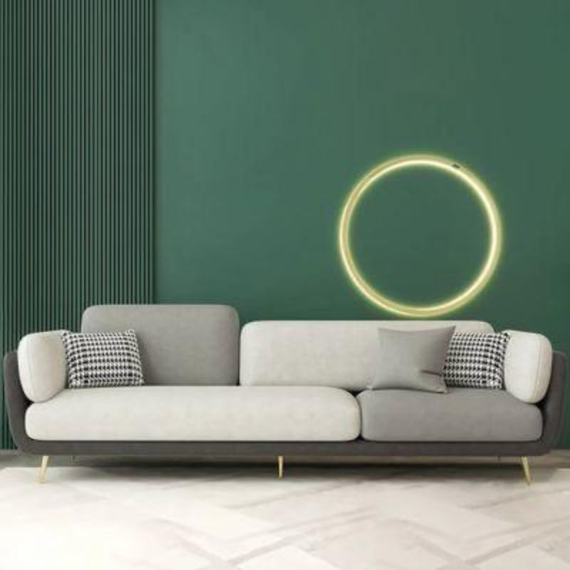 Gray sofa by Oak Insidewith patterned cushions against a green wall with a circular light fixture.