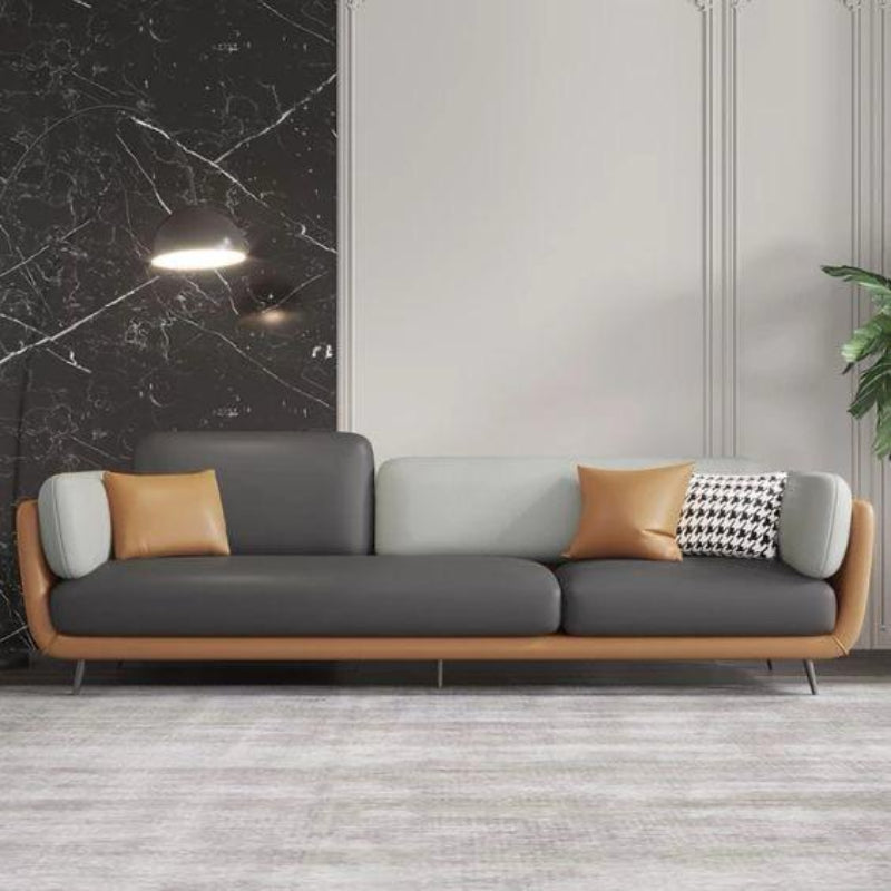 Gray and brown sofa oak inside with decorative pillows in a modern room with marble wall.